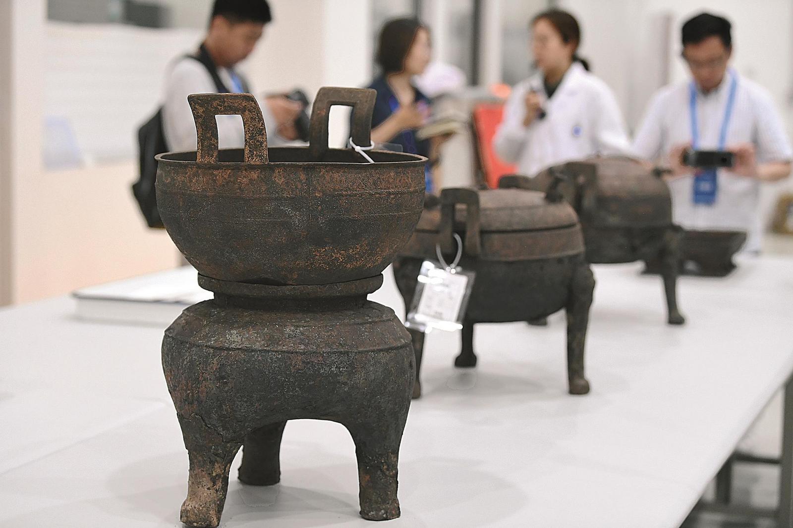 在淮南武王墩墓发掘现场，考古人员向记者介绍出土的青铜器。本报记者 徐旻昊 摄