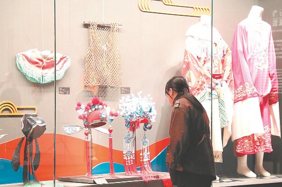 博物馆内，游客正在参观戏服、盔帽等展品。